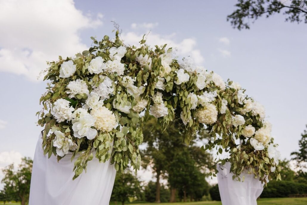 greenery and white flowers on wedding ceremony arch